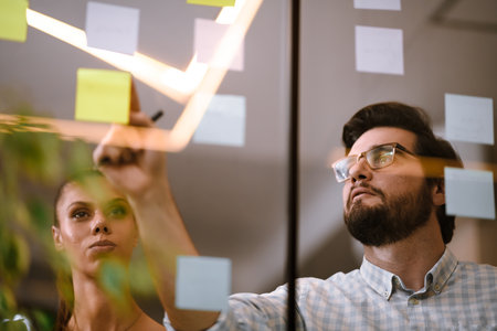 Team members discussing ideas on sticky notes during a brainstorming session in a modern office...