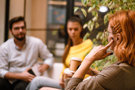 Group discussion in a cozy cafe setting focusing on a thoughtful woman holding coffee as friends listen nearbyの写真素材