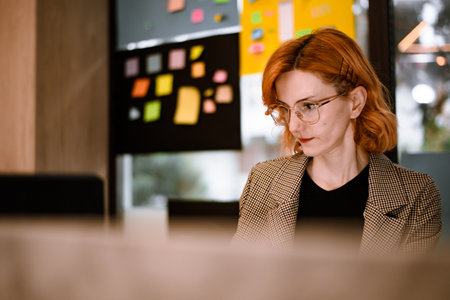 Young woman working in a creative office space with colorful sticky notes on display during daytimeの写真素材