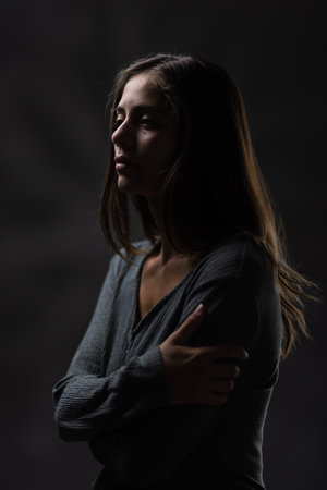 Elegant young woman in a contemplative pose, studio portrait with dramatic lightingの写真素材