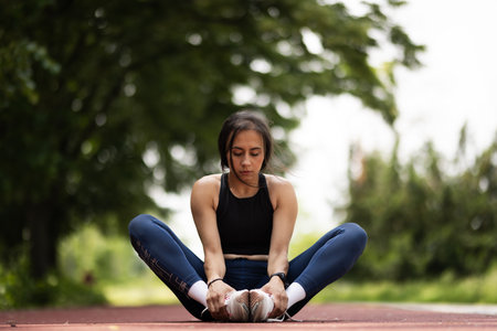 Young woman in athletic wear stretching outdoors on a warm sunny dayの写真素材