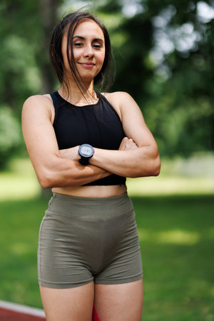 Confident Female Athlete Posing Outdoors in Sportswear on a Sunny Dayの写真素材