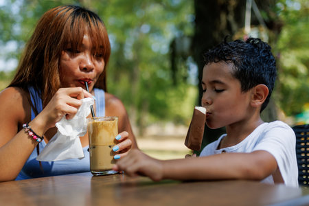 Mother and son enjoying a relaxing outdoor treat with iced coffee and ice cream