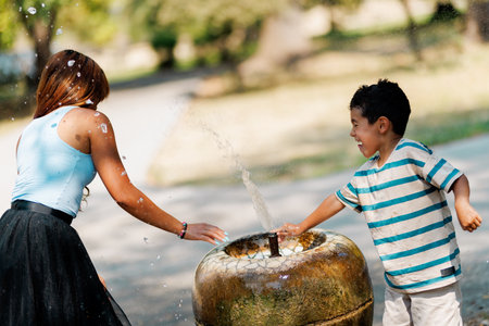 Two people enjoying playful moments around a fountain on a sunny dayの写真素材