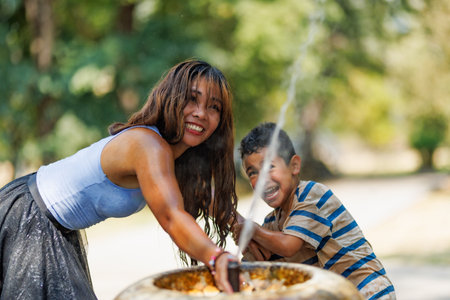 Mother and child enjoying playful moments with water outdoors on a sunny dayの写真素材