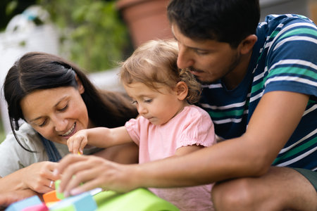 Parents and young daughter engaging in fun and educational activity together outdoorsの写真素材