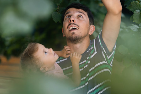 Father with child in a forest looking at something in the tree branchesの写真素材