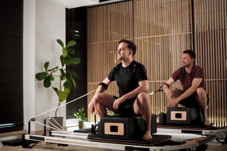 Pilates enthusiasts practicing strength training on reformer machines in a modern studio environment