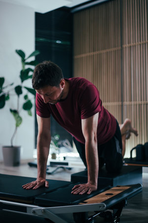 Focused workout on reformer pilates machine in modern studio during daytimeの写真素材