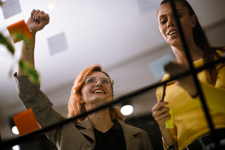 Creative brainstorming session at a modern office with colleagues sharing ideas and collaborating while using colorful sticky notes during the dayの写真素材