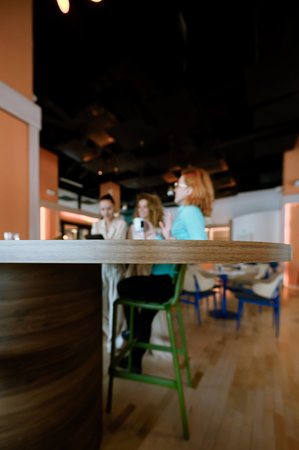 Businesswomen engage in conversation at a contemporary workspace during a casual meeting while...