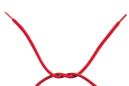 Two red shoelaces are tied together in a neat knot, forming a V shape. The background is plain...