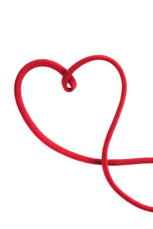 A red rope is creatively twisted into the shape of a heart, lying flat against a plain white...