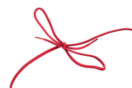 A vibrant red shoelace is expertly tied into a neat bow, resting on a smooth white surface. The...