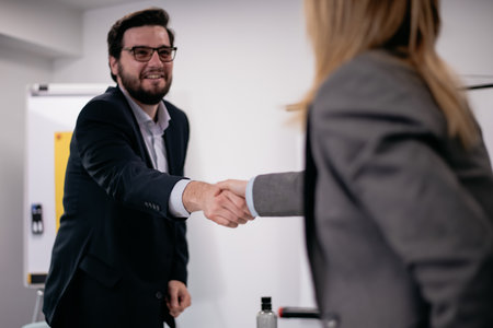 Business professionals shaking hands during a formal meeting in a modern office spaceの写真素材