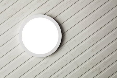 A circular light fixture is mounted on a white wood panel ceiling, providing a clean and...