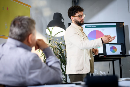 Businessman presenting customer analytics in a modern office environment during a strategic meeting with colleaguesの写真素材