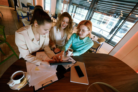 Businesswomen collaborating in a modern workspace, discussing ideas and reviewing documents during a productive meeting in the heart of the cityの写真素材