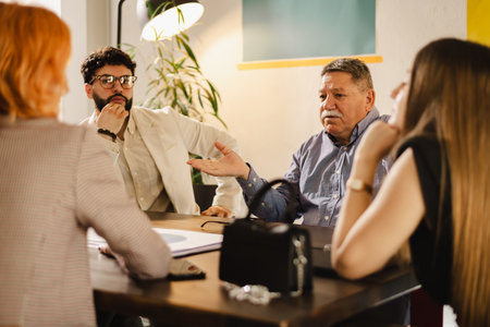 Group discussion in a modern office setting with professionals engaged in deep conversation during a meeting in the afternoonの写真素材