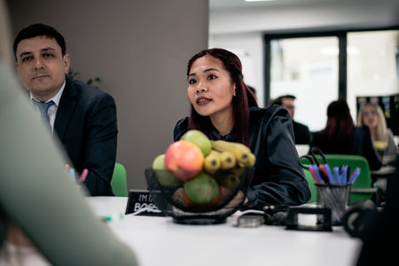 Colleagues in a workplace having a discussion at a desk with a fruit basket