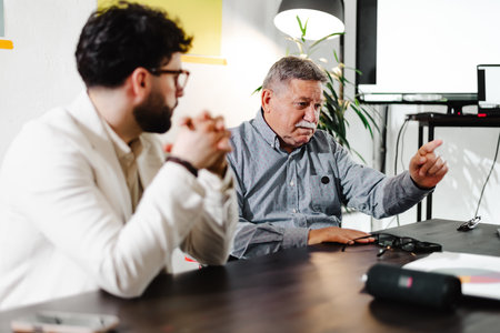 Two businessmen engage in a discussion during a meeting in a modern office setting, sharing ideas...