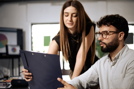 Business meeting between two professionals discussing project details in a bright office environment during daytimeの写真素材