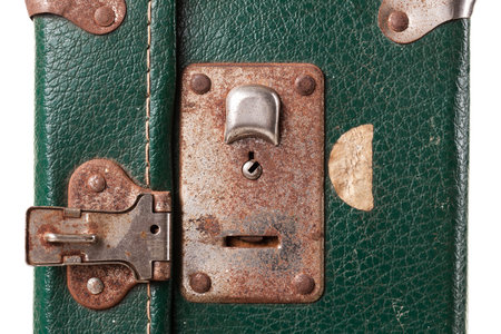 Close-up view of a vintage green suitcase lock displaying rusted metal parts and signs of aging. The lock mechanism invites curiosity about its history and travelsの写真素材