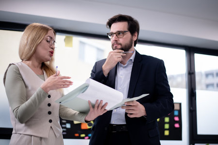 Business professionals discussing documents and sharing ideas during a meeting in a modern office...