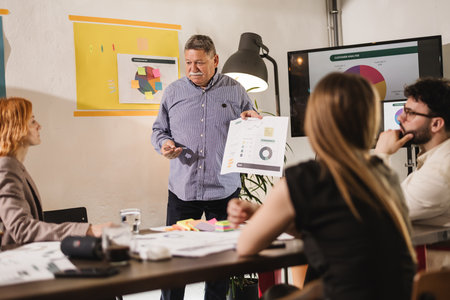 Businessman presents marketing strategy during a team meeting in a modern office space with engaging...