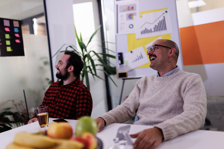 Business meeting in a modern office with engaging discussion and laughter among colleagues in a bright environmentの写真素材