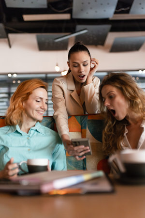 Exciting business meeting in a modern cafe with three women engaged in conversation and sharing ideasの写真素材