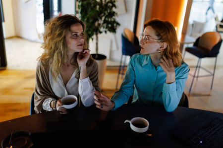 Businesswomen having a conversation over coffee in a modern office space during the morning hoursの写真素材