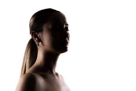 Elegant silhouette portrait of a woman in profile against a white background, conveying calm beauty, grace, and subtle sophisticationの写真素材