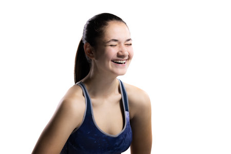 Joyful young woman in sports outfit laughs during a photoshoot, isolated on whiteの写真素材