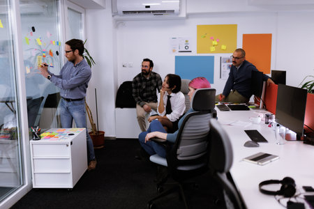 Business team collaborates in a modern office space during a brainstorming session with sticky notes and digital devicesの写真素材