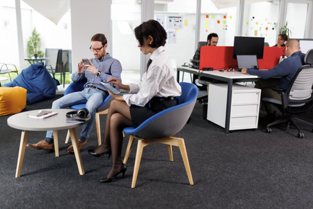 Business professionals engage in conversation while collaborating in a modern office space with...