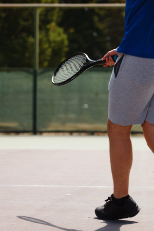 Player prepares for a tennis match on outdoor court during sunny afternoon, showcasing athletic gear...