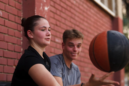 Basketball players engaged in a practice session at an outdoor court in the late afternoon sun, showing focus and teamwork during their trainingの写真素材