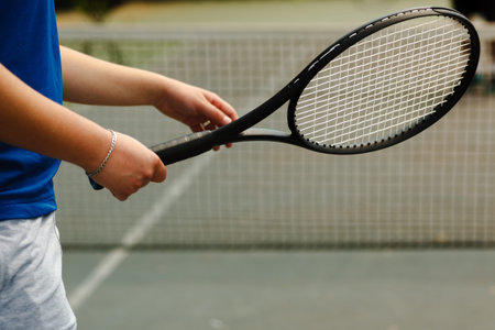 Player prepares for a tennis serve while standing on the court during a sunny day in a local sports...