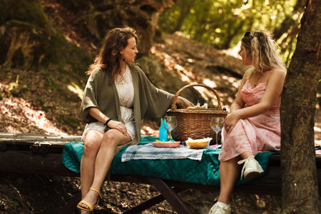 Enjoying a summer picnic in a lush forest with friends and delicious foodの写真素材