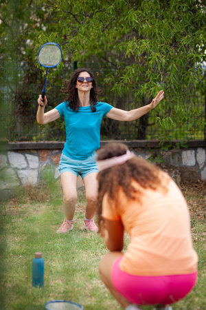 Women enjoying a friendly badminton match in a sunny garden, showcasing skill and athleticism during a leisurely afternoonの写真素材
