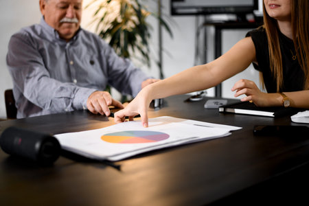Business discussion in a modern office setting with a businessman and a colleague analyzing data charts and reports during a meetingの写真素材