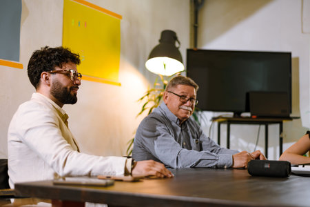 Meeting in a modern office setting with focused discussions among colleagues of various backgrounds late in the afternoonの写真素材