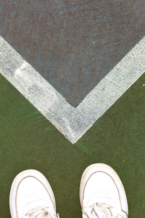 Shoes on a green tennis court with white markings at midday, signaling readiness for an active game session with friendsの写真素材