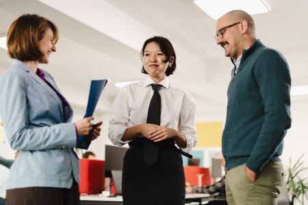 Business professionals in casual discussion at a modern office setting during the day, sharing ideas and strategies for teamwork and collaborationの写真素材