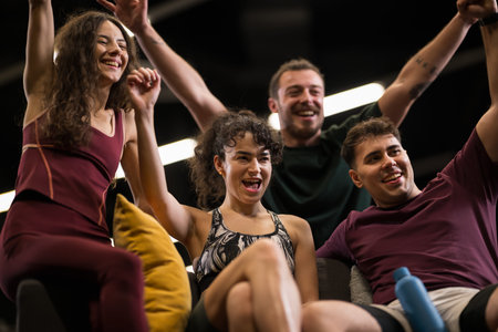Group of friends celebrating after a fitness class in a gym with bright lights and a lively atmosphere during the evening sessionの写真素材