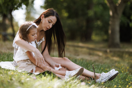 Mother caring for her young daughter in a park settingの写真素材