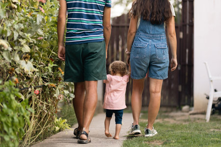 Rearview of a family walking together along a garden path providing support and shared moments