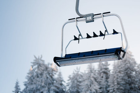 Ski lift moves over snow-covered trees at a mountain resort during winter season