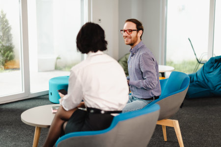 Business professionals engage in discussion in a modern office setting with a casual atmosphere during a weekday morning meeting